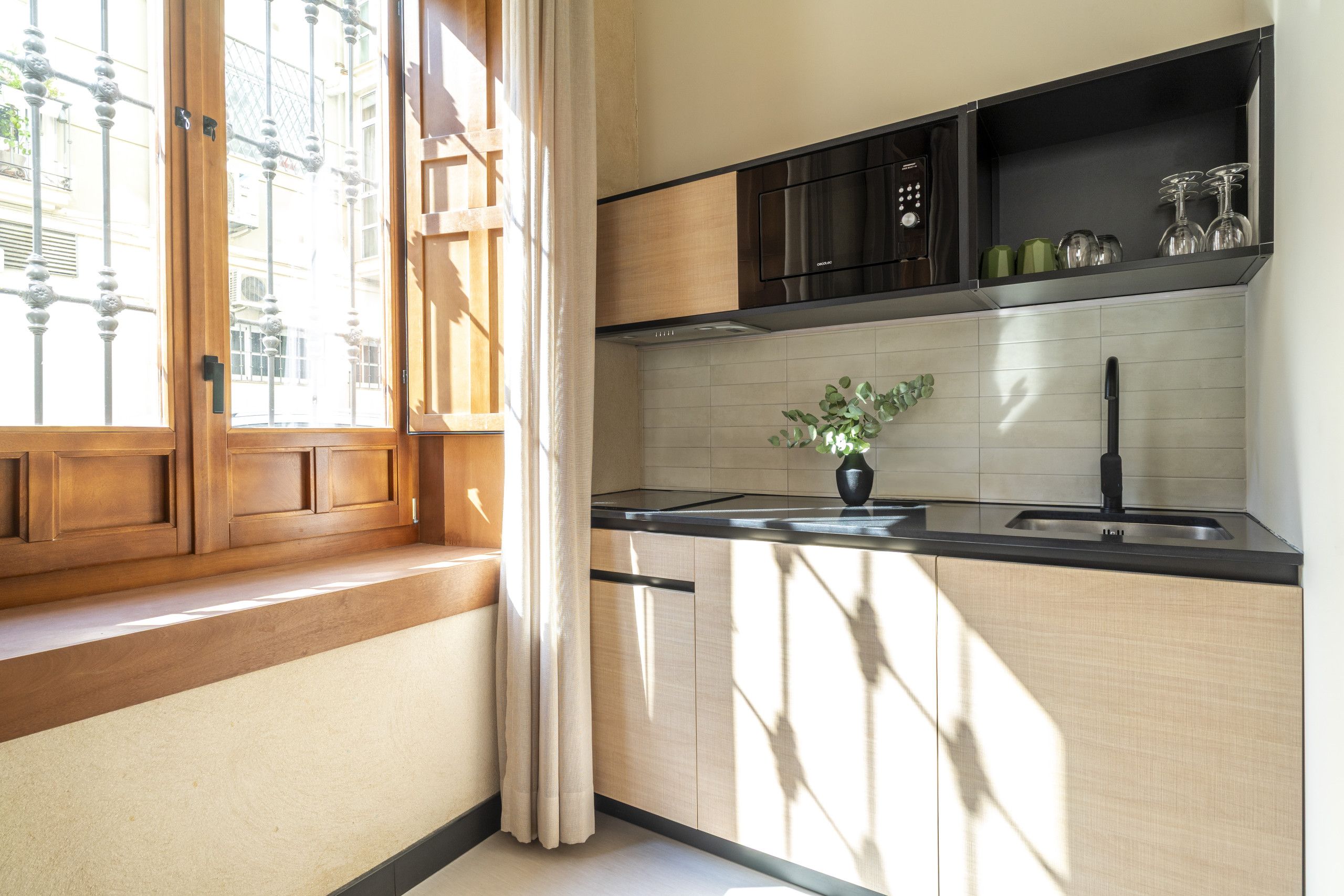 A kitchen with a window, a plant on the counter, and a built-in oven.
