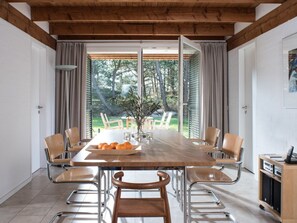 A dining area with a wooden table, chairs, and a view of the outdoors. - Holiday Home With 4 Bedrooms (St. Peter-Ording)