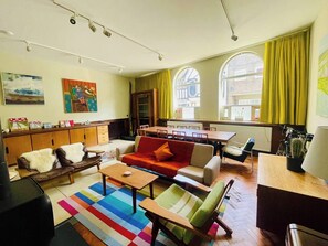 A modern living room with a sofa, armchairs, a coffee table, and a dining area with a table and chairs. - Historic Harwich Post Office w/Old Town Character (Essex)