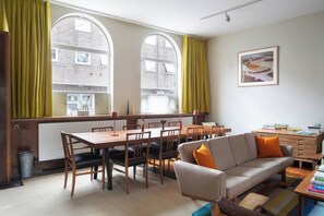 A room with a dining table, chairs, a sofa, and a radiator. - Historic Harwich Post Office w/Old Town Character (Essex)