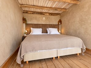 A bedroom with a wooden ceiling, a bed with white bedding, and two bedside lamps.
