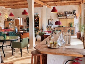 Un interior rústico con una mesa de comedor de madera, sillas y lámparas colgantes.