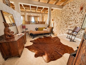 A room with a sofa, a leather rug, a wooden cabinet, and a chair.