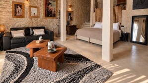 Ein geräumiges Zimmer mit einem großen Bett, einer Couch und einem Couchtisch. An den Wänden hängen Bilder in Rahmen, und die Decke besteht aus Holz.