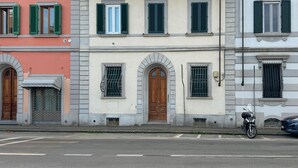 Straßenansicht eines Gebäudes mit Bogenfenstern und einer Holztür.