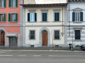 A street view with a building featuring arched windows and a wooden door. - 20 mins from Duomo • Outside ZTL • Easy Parking (FIRENZE)