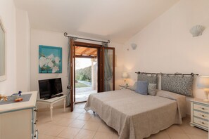Ein Schlafzimmer mit einem Bett, Nachttischen, einem Fernseher und Blick ins Freie.