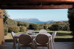 An outdoor patio with a table and chairs, overlooking a mountainous landscape and the sea. - Villetta Rosella by Wonderful Italy (Golfo Aranci)
