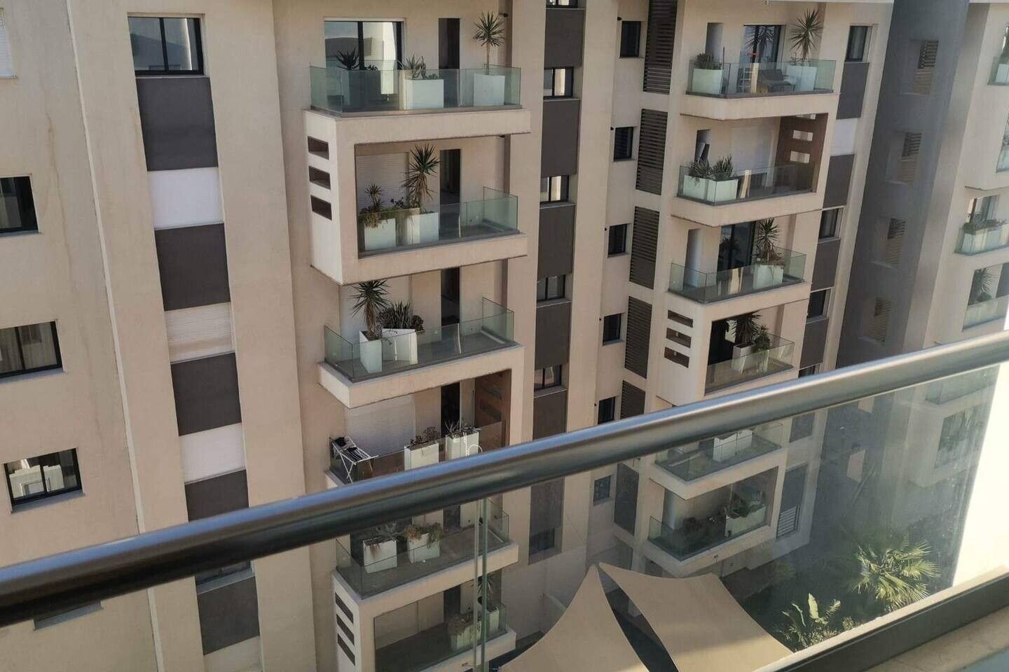 A multi-story residential building with balconies, each with potted plants.