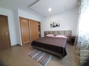 Ein Schlafzimmer mit Bett, Kleiderschrank, Nachttisch und Teppich.