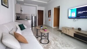 A modern living room with a sofa, coffee table, and a flat-screen TV mounted on the wall. - Elegant High-End Apartment (Tunis Governorate)