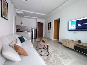 Ein modernes Wohnzimmer mit einer Couch, einem Couchtisch und einem an der Wand befestigten Flachbildfernseher.