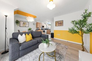 A modern living room with a grey sofa, a white coffee table, and a yellow accent wall. - Welcome to our  2-bedroom apartment in "Hayes, West London" perfect for up to 4–5 guests. Ideal for families, business travelers, couples and small groups. (Greater London)