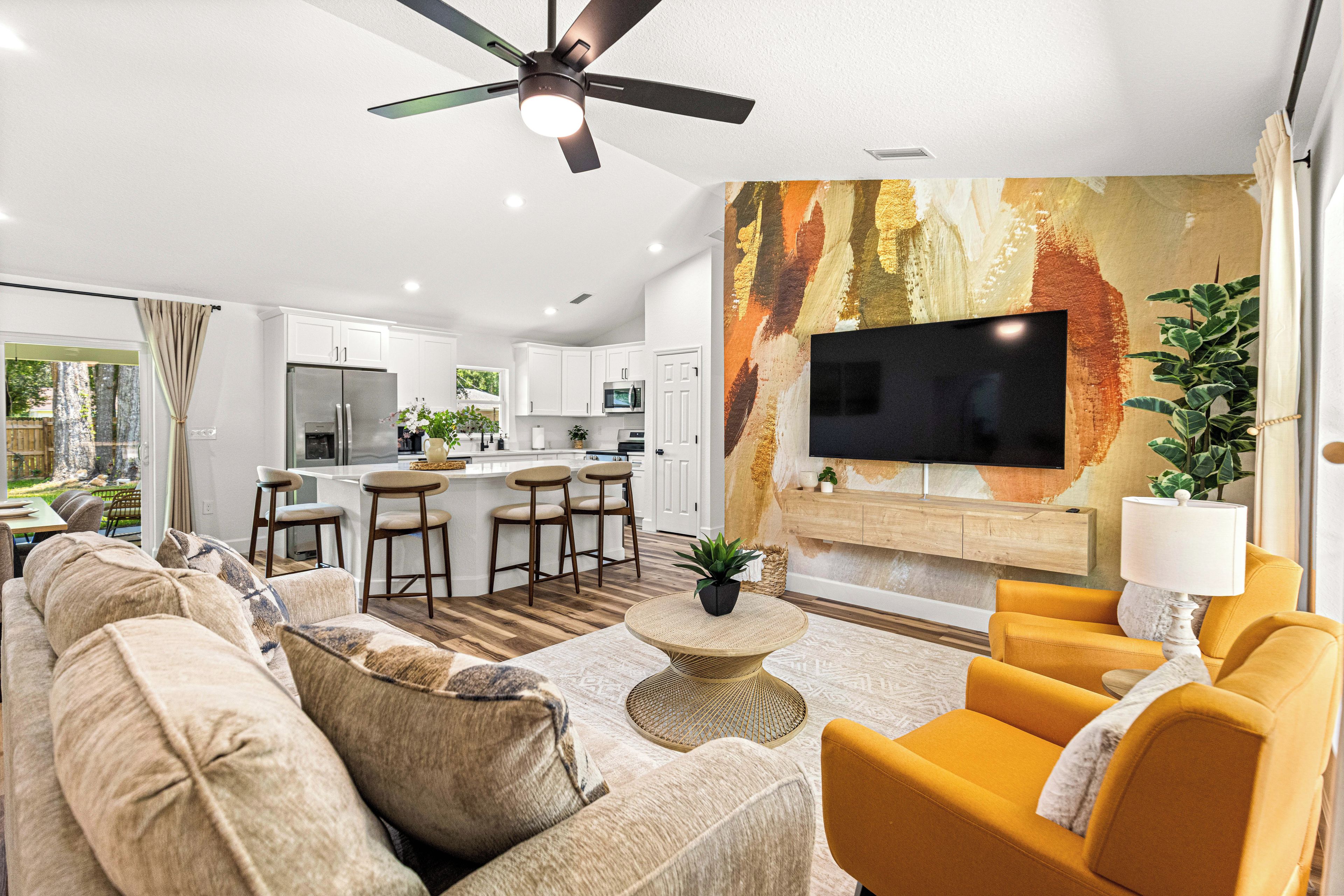 A modern living room with a sofa, armchairs, a coffee table, and a TV mounted on a textured wall.