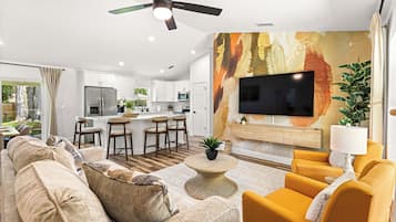 A modern living room with a sofa, armchairs, a coffee table, and a TV mounted on a textured wall.