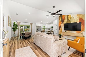 A modern living room with a sofa, a yellow armchair, and a flat-screen TV mounted on the wall. - NEW 3 bedroom-6 miles to WEC-CLEAN-Pet friendly (Ocala)