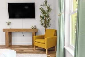 A living room with a yellow armchair, a wooden coffee table, a flat-screen TV, and a potted plant. - NEW 3 bedroom-6 miles to WEC-CLEAN-Pet friendly (Ocala)
