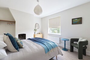A bedroom with a bed, a dresser, a chair, a window, and a painting on the wall.