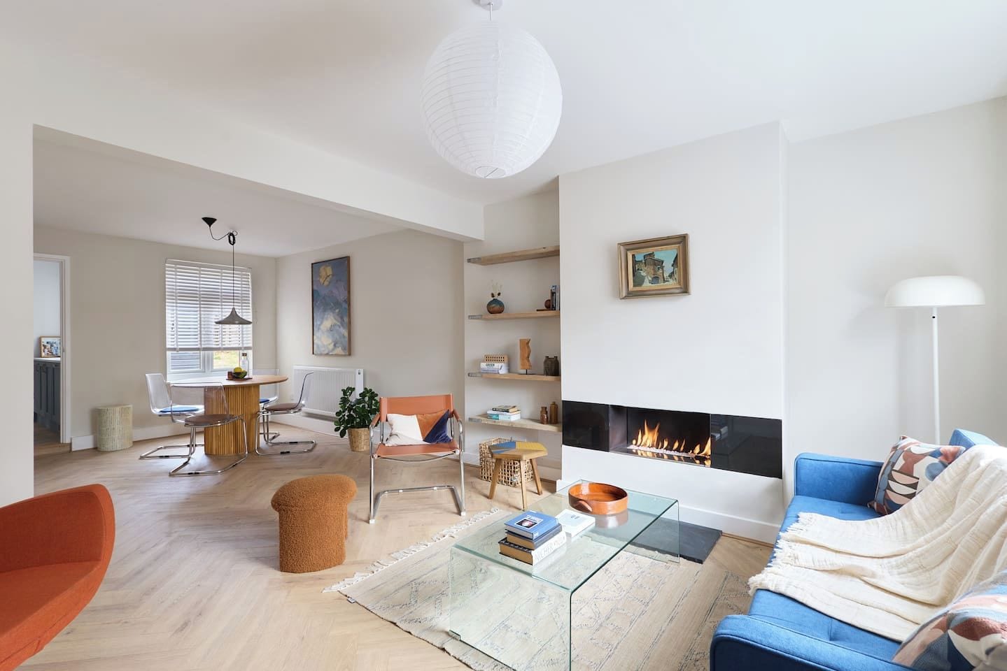 A modern living room with a fireplace, seating area, and a dining space.