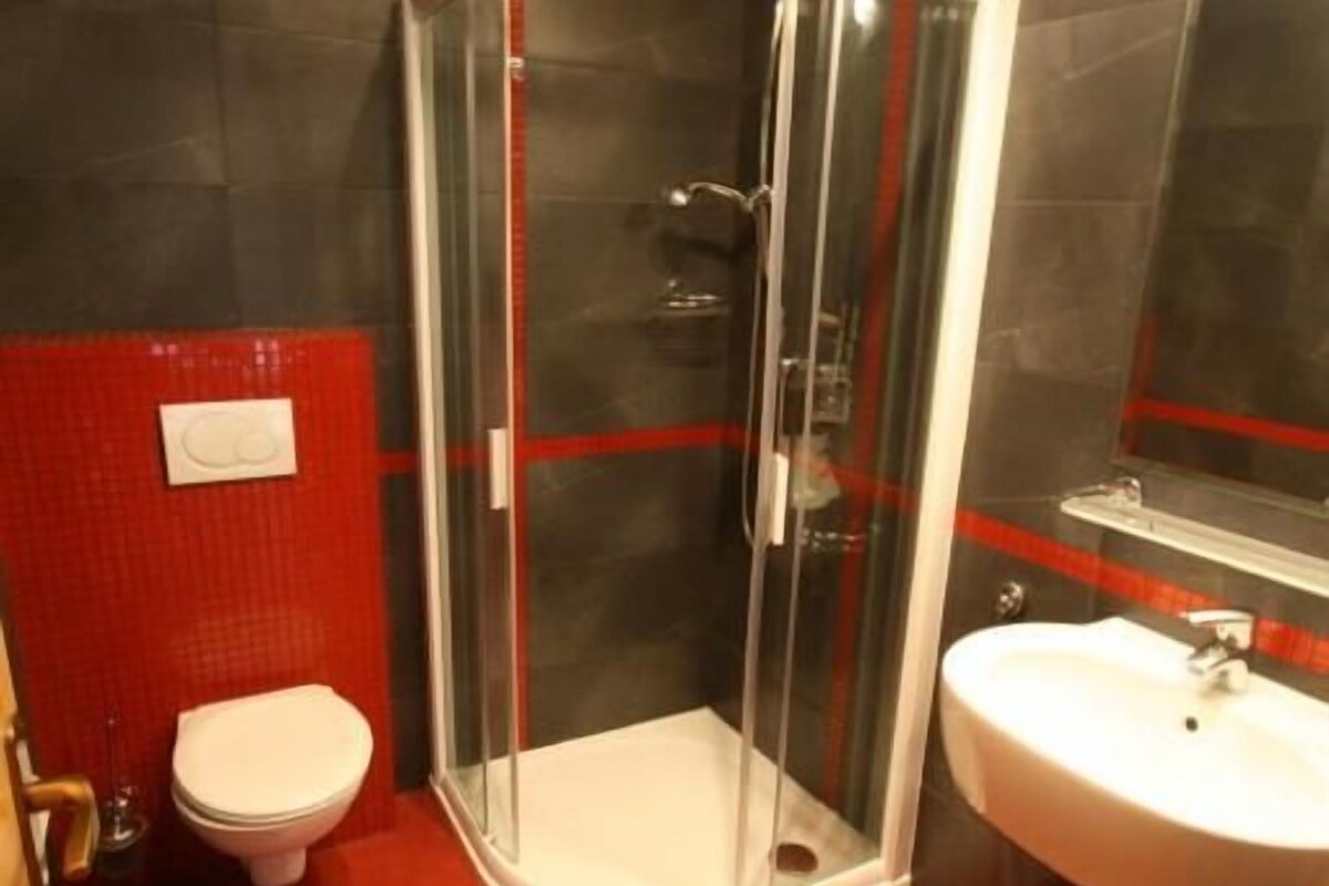 Un baño con ducha de vidrio, inodoro y lavamanos.