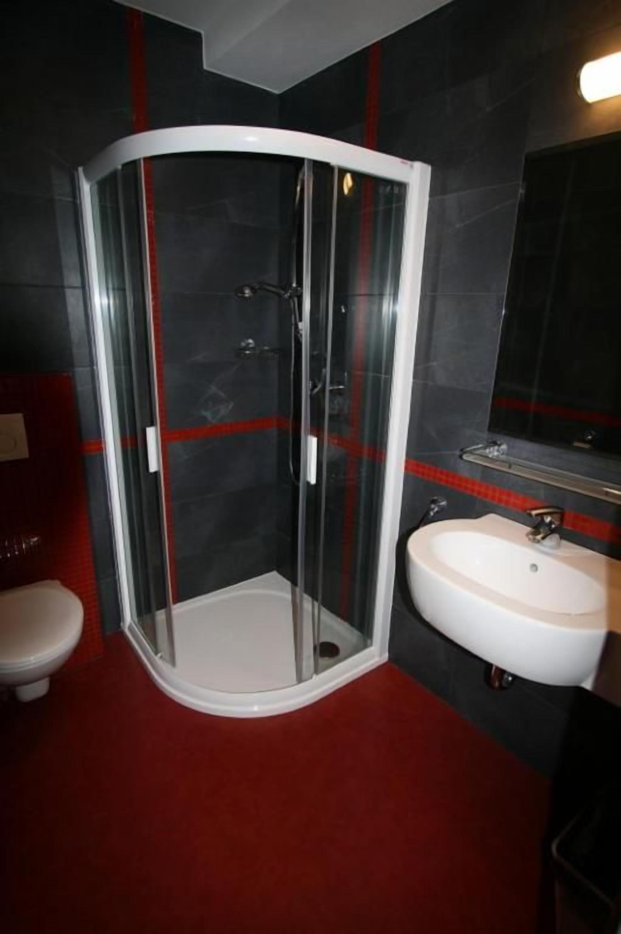 A bathroom with a glass-enclosed shower, a white sink, and a toilet.