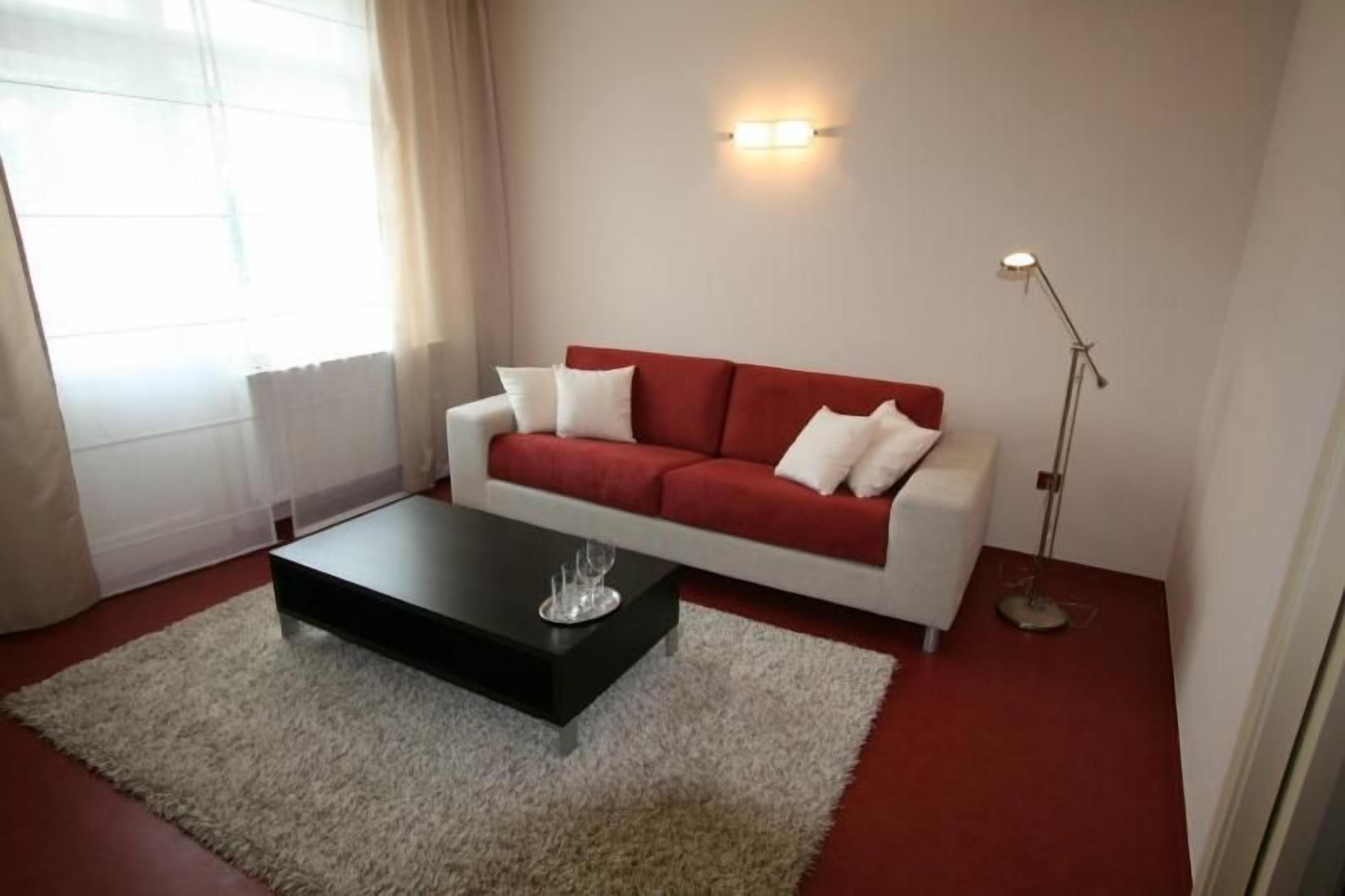 A living room with a red sofa, a black coffee table, a white rug, and a floor lamp.