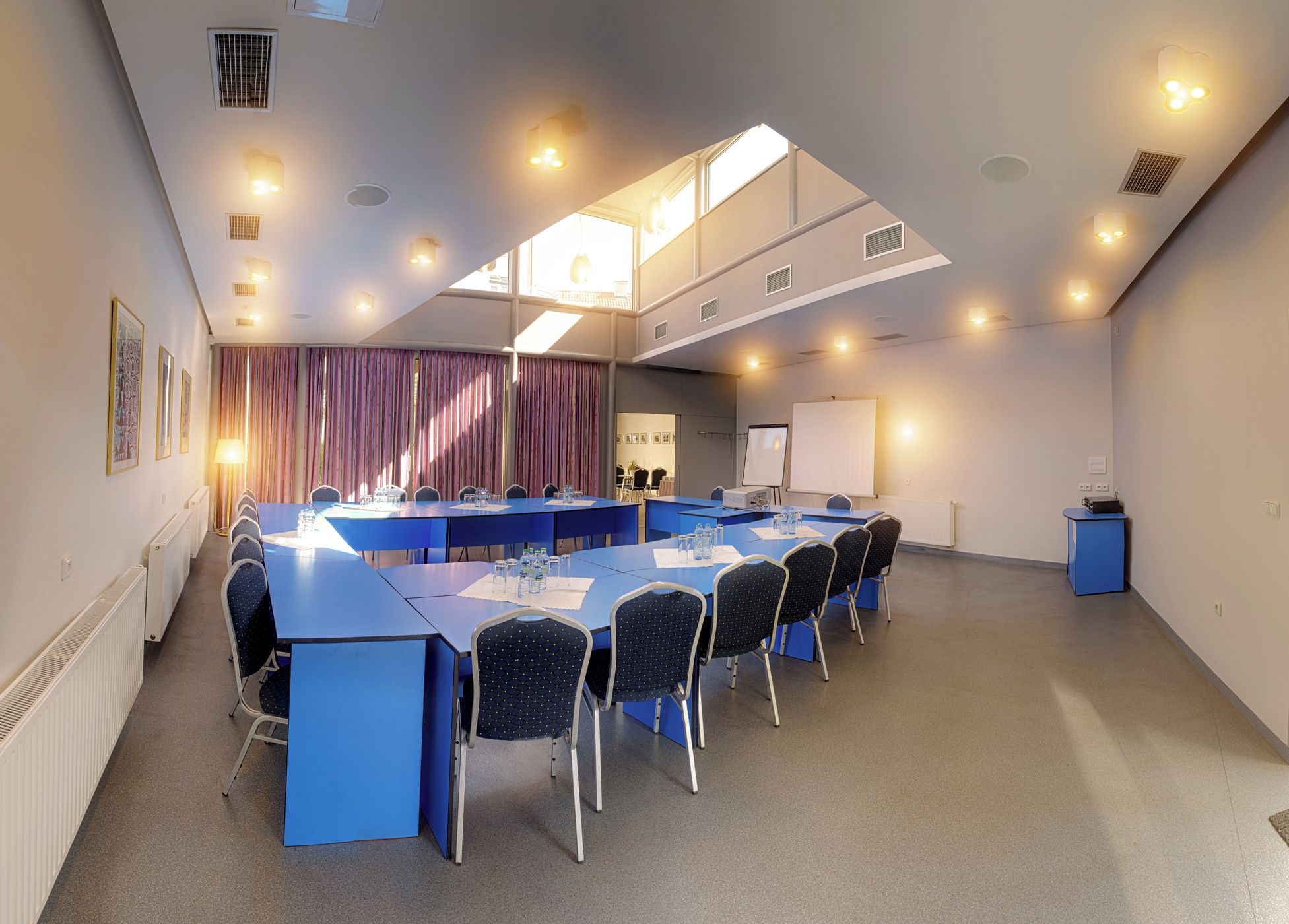 A conference room with a long table, chairs, a whiteboard, and a projector.