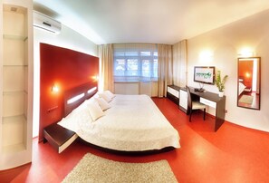 Una habitación de hotel con cama, escritorio, silla y televisor.