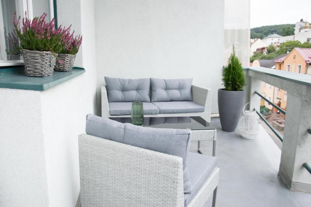 A balcony with wicker furniture, potted plants, and a view of buildings.