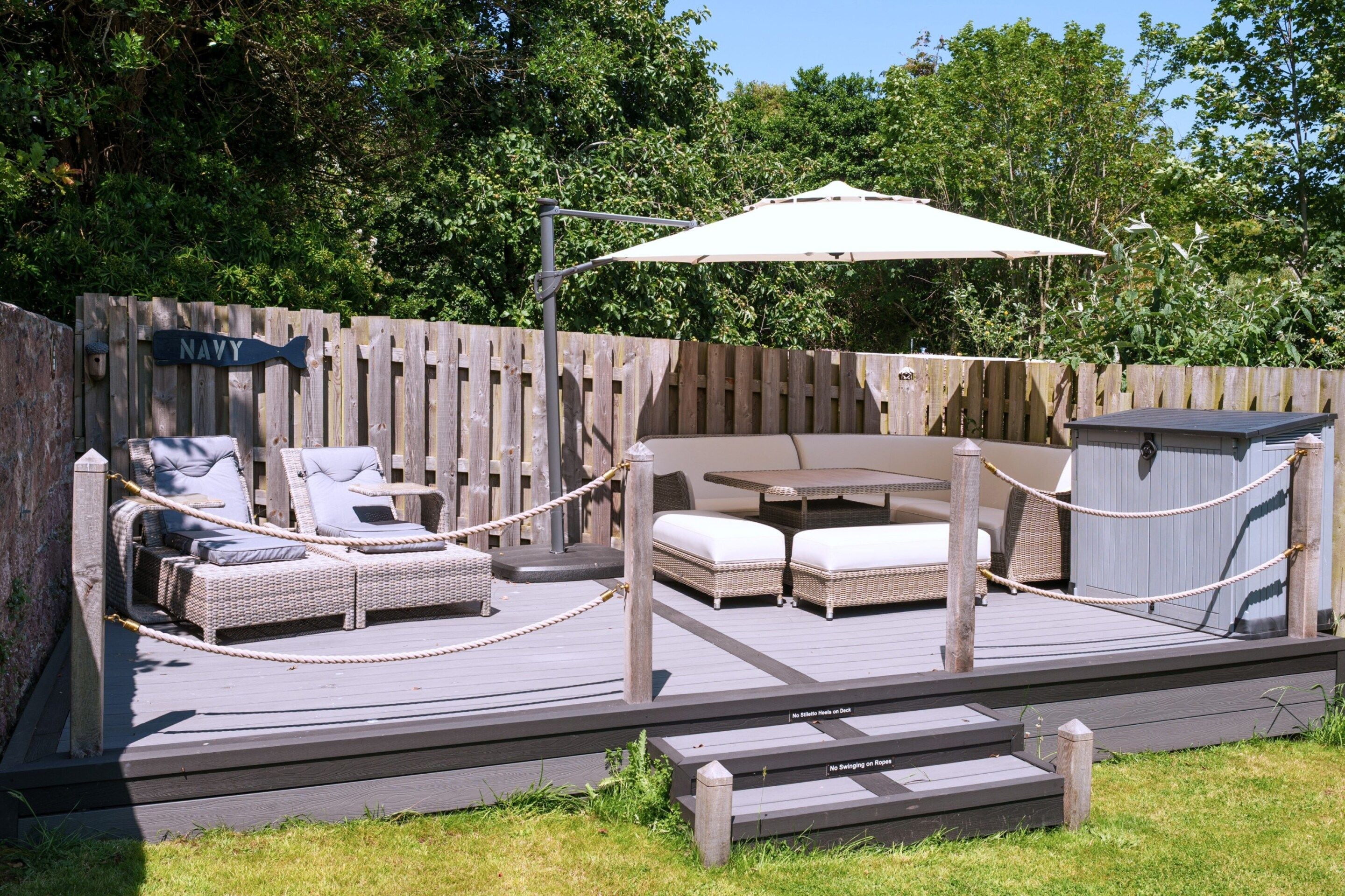 A deck with outdoor furniture, including a sofa and chairs, and a small table.