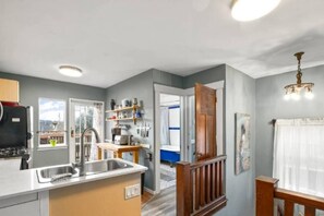 A kitchen with a built-in sink, wooden cabinets, and a view to the outside. - Charming 2BR Kisilano Duplex | Near Jericho Beach (Vancouver)