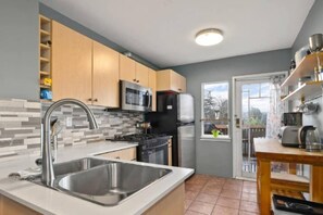 A modern kitchen with a stainless steel sink, a microwave, a refrigerator, and a stove. - Charming 2BR Kisilano Duplex | Near Jericho Beach (Vancouver)