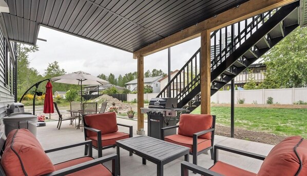 Une terrasse extérieure avec un barbecue, un espace salon et un escalier.