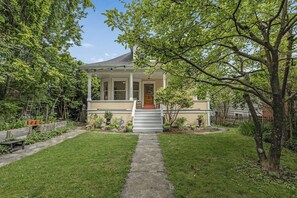 Ein eingeschossiges Haus mit Veranda, kleinem Vorgarten und Holzzaun.