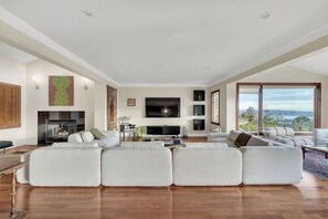 A spacious living room with a large sectional sofa, a flat-screen TV, and a fireplace. - West Vancouver Getaway | Pool & Panoramic Views (West Vancouver)