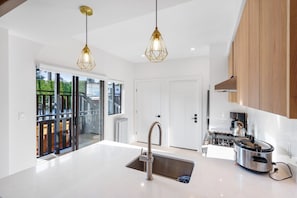 A modern kitchen with a large island, stainless steel appliances, and pendant lighting. - Charming 2BR Jericho Home | Private Deck with BBQ! (Vancouver)