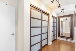 A hallway with sliding glass doors, a wooden floor, and a mirror on the wall. - Elegant 3BR Family Home - Prime Vancouver Location (Vancouver)