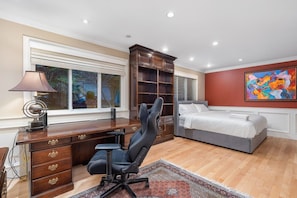 A bedroom with a bed, desk, chair, and artwork on the wall. - Upscale West Vancouver Estate with Movie Room (West Vancouver)