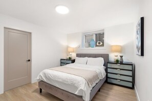 A bedroom with a bed, nightstands, a window, and a door.
