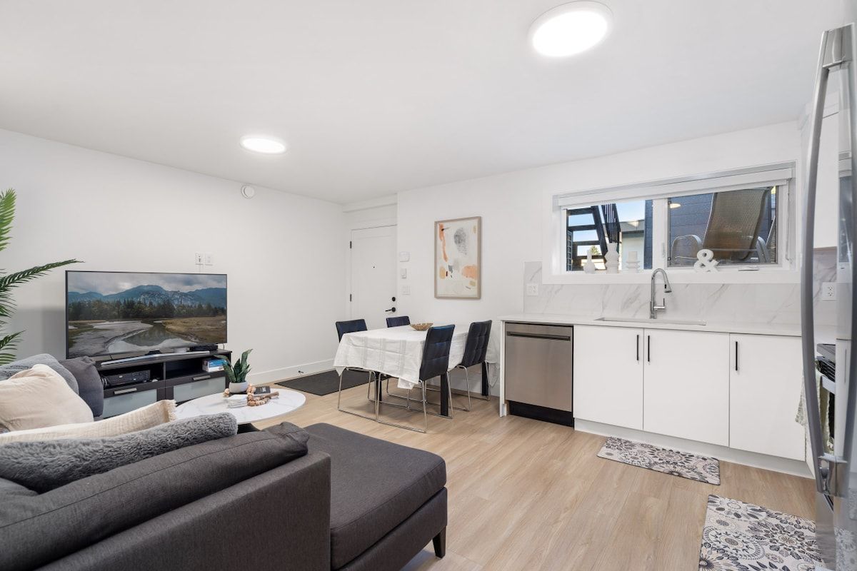 A modern living room with a sofa, a TV, and a dining area with a table and chairs.