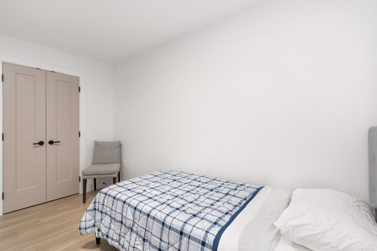 A bedroom with a bed, a chair, and a wardrobe.