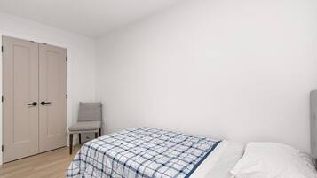 A bedroom with a bed, a chair, and a wardrobe.
