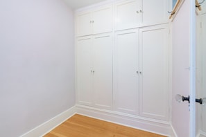 Ein Zimmer mit einem weißen Wandschrank, Holzboden und einer weißen Tür mit Griff.