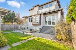 A modern two-story house with a covered patio, a small garden, and a wooden fence. - Central Luxury Home - Views and Private Cinema (Vancouver)