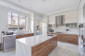 A modern kitchen with a large island, built-in appliances, and a view of the outside. - Central Luxury Home - Views and Private Cinema (Vancouver)