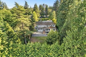 A two-story house surrounded by dense forest. - Grand 4BR Point Grey Manor - Walk to Beaches (Vancouver)