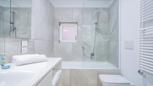 Ein modernes Badezimmer mit einer Glaskabine zur Dusche, einem weißen Waschbecken und einer Toilette.