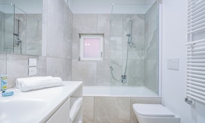 Ein modernes Badezimmer mit einer Glaskabine zur Dusche, einem weißen Waschbecken und einer Toilette.
