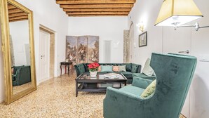 Ein Wohnzimmer mit einem grünen Sofa, einem Couchtisch, einem Spiegel und einem Bild an der Wand.