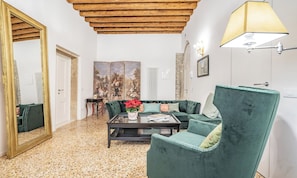 Ein Wohnzimmer mit einem grünen Sofa, einem Couchtisch, einem Spiegel und einem Bild an der Wand.